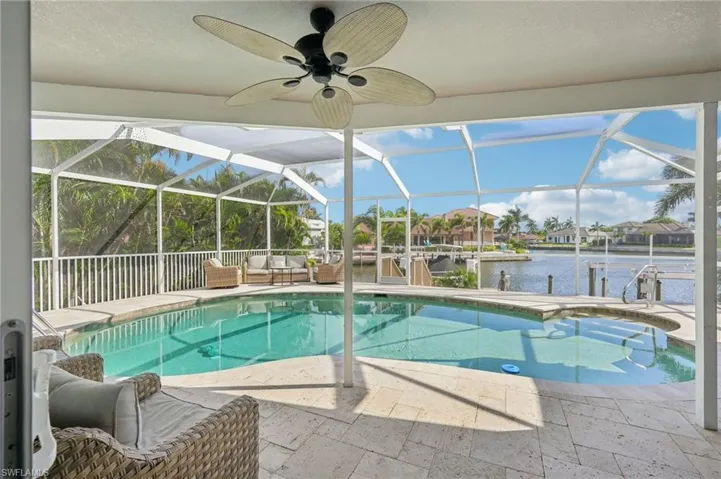 Outdoor pool featuring a water view, a boat dock, a patio, boat lift, and a lanai