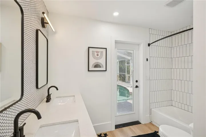 Full bath with wood finished floors, double vanity, bathing tub / shower combination, and recessed lighting