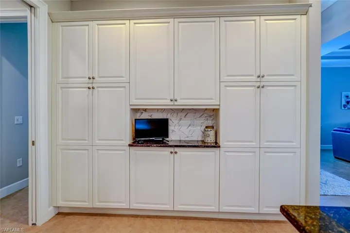 Kitchen featuring backsplash, white cabinets, dark stone counters, and light tile patterned floors