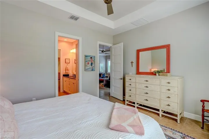 Bedroom with light tile patterned floors, ceiling fan, and ensuite bathroom
