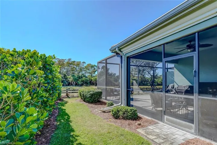 View of green lawn with a lanai, a sunroom, and ceiling fan