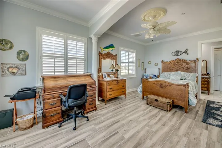 Bedroom featuring wood finish floors, ornamental molding, a ceiling fan, and a desk