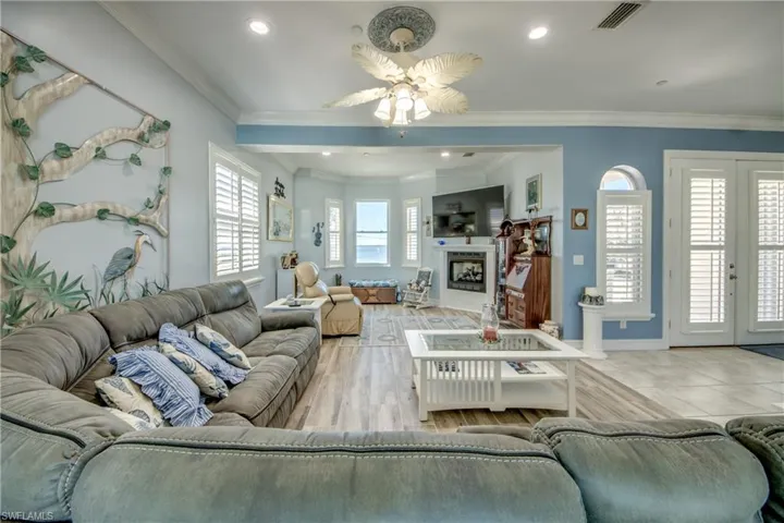 Living room featuring crown molding, a fireplace, recessed lighting, and a ceiling fan