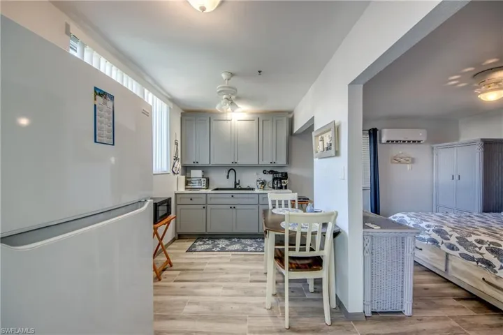 Kitchen featuring freestanding refrigerator, gray cabinetry, wood finish floors, and light countertops