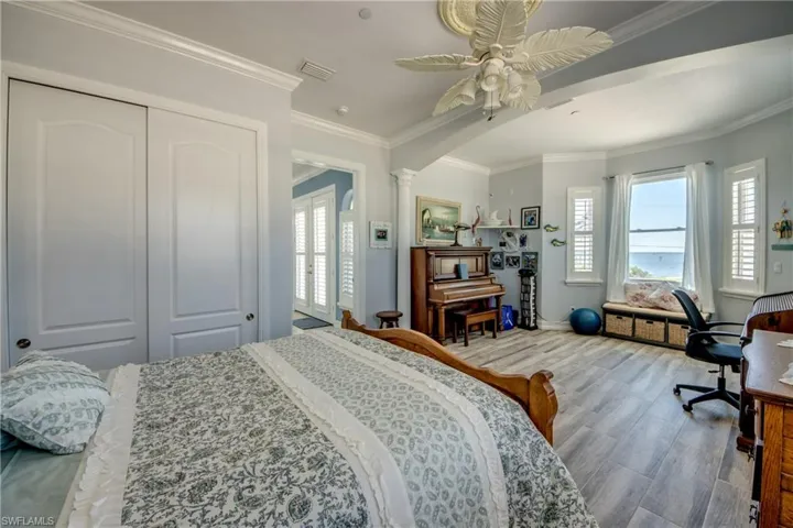 Bedroom with crown molding, multiple windows, ceiling fan, wood finished floors, and a desk
