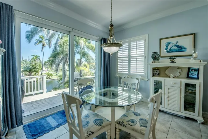 Dining area with crown molding, a water view, and light tile patterned flooring