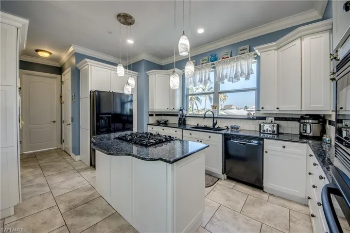 Kitchen featuring ornamental molding, black appliances, decorative backsplash, white cabinetry, and dark stone countertops