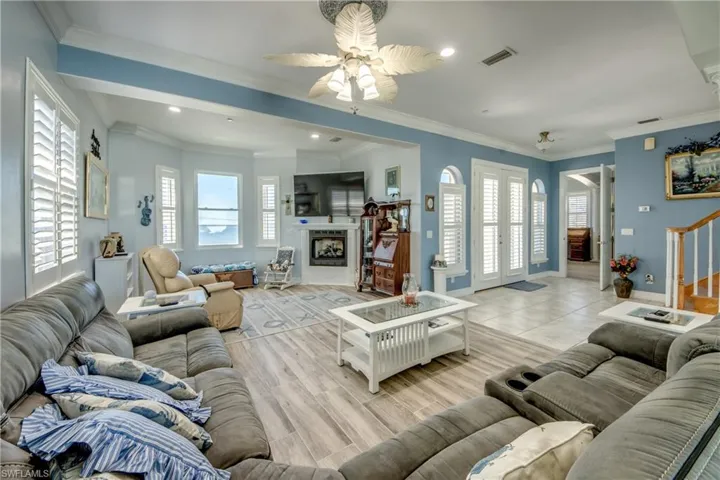 Living area with crown molding, recessed lighting, stairway, ceiling fan, and a fireplace
