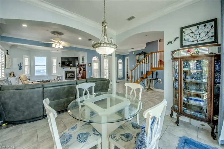 Dining room featuring arched walkways, stairway, a fireplace, ornamental molding, and ceiling fan