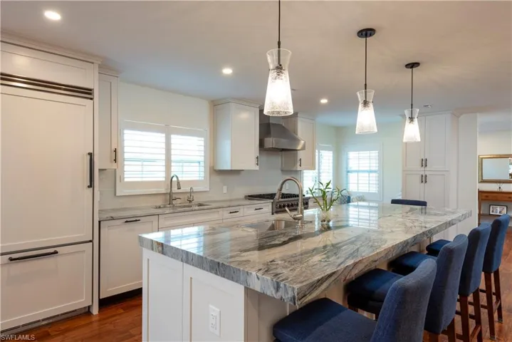 Kitchen featuring integrated appliances, stone counter tops and dual sinks