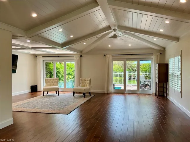 Living area with vaulted ceiling, recessed lighting and doors leading to private pool