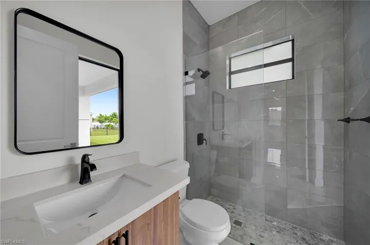 Bathroom with toilet, a shower with door, and vanity