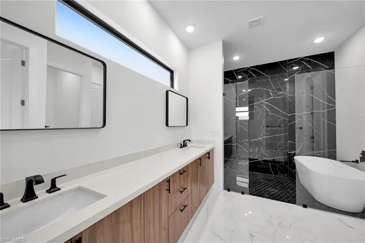 Bathroom featuring tile patterned flooring, a tile shower, and dual vanity
