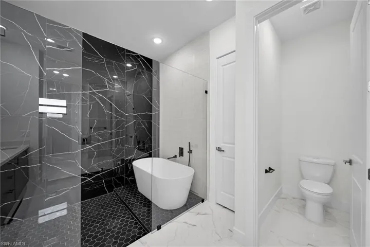 Bathroom with vanity, tile patterned flooring, a tile shower, tile walls, and toilet