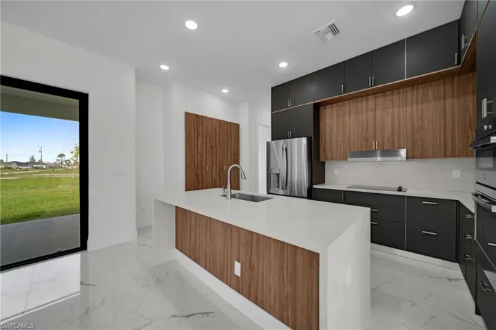 Kitchen featuring sink, black appliances, light tile patterned flooring, and a kitchen island