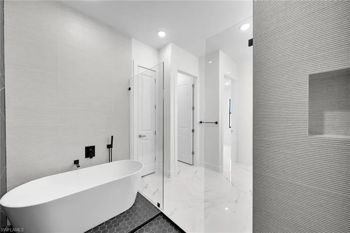 Bathroom featuring tile walls, tile patterned flooring, and a tub to relax in