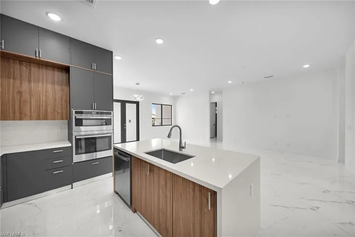Kitchen with sink, appliances with stainless steel finishes, a center island with sink, and light tile patterned flooring