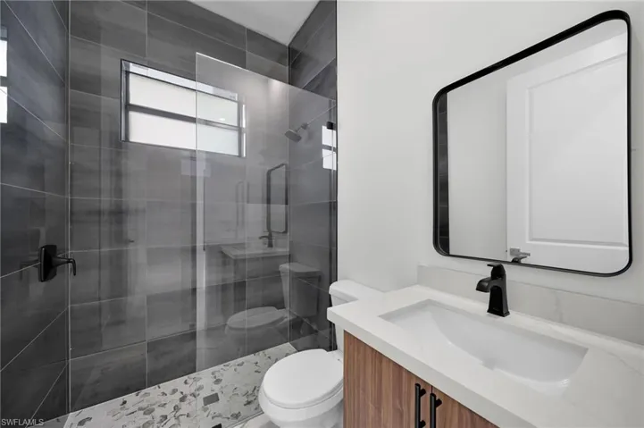 Bathroom with toilet, vanity, and a shower with shower door