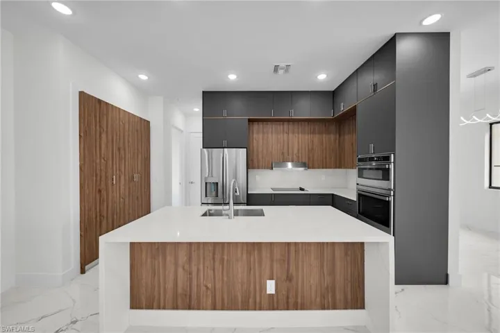 Kitchen with appliances with stainless steel finishes, light tile patterned flooring, an island with sink, and sink