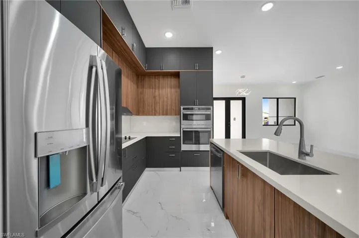 Kitchen featuring light tile patterned floors, sink, and stainless steel appliances