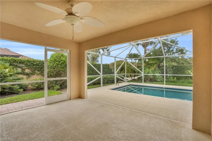 View of pool with a patio, glass enclosure, and ceiling fan