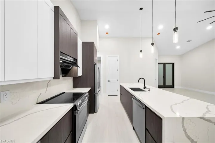 Kitchen with modern cabinets, stainless steel appliances, light stone countertops, and two tone color scheme