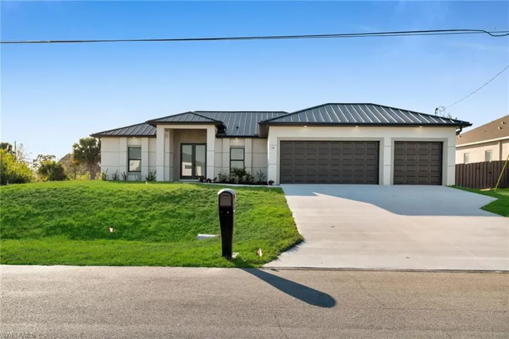 View of front of property with concrete driveway, stucco siding, a garage, and a standing seam roof