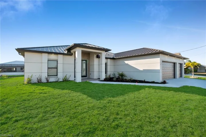 Prairie-style house featuring a standing seam roof, a front lawn, and stucco siding