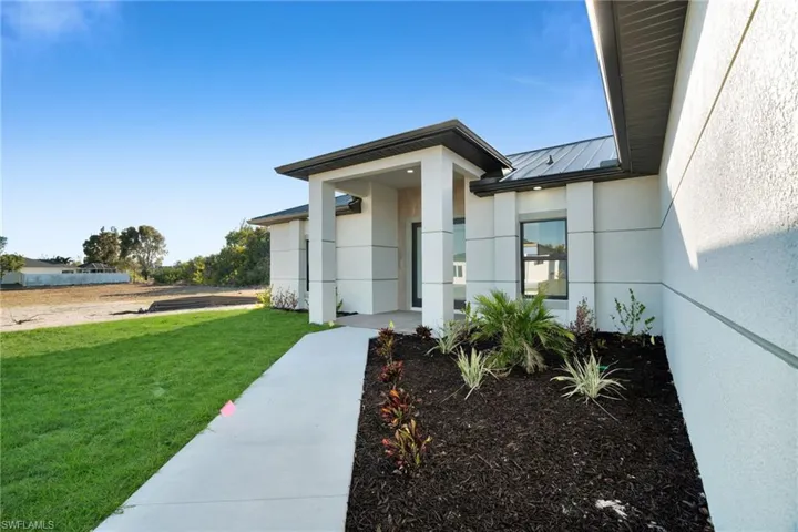Property entrance featuring a standing seam roof, a yard, and stucco siding