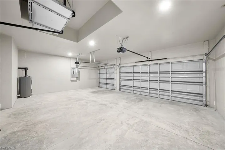 Garage featuring electric water heater, recessed lighting, electric panel, and a garage door opener