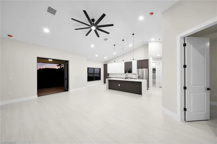 Unfurnished living room featuring a ceiling fan, vaulted ceiling, and recessed lighting