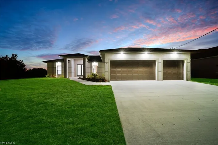 Modern home with an attached garage, driveway, stucco siding, and a lawn
