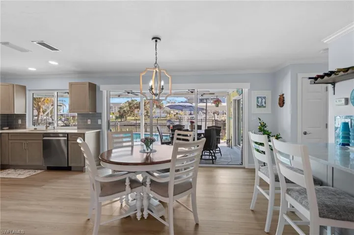 Dining space featuring crown molding, a chandelier, sink, and light hardwood / wood-style flooring