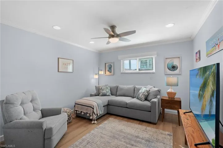 Den with crown molding, ceiling fan, and light hardwood / wood-style floors