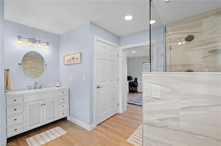 Bathroom with hardwood / wood-style flooring, vanity, and a tile shower