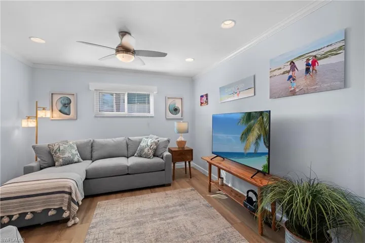 Den featuring crown molding, light hardwood / wood-style flooring, and ceiling fan