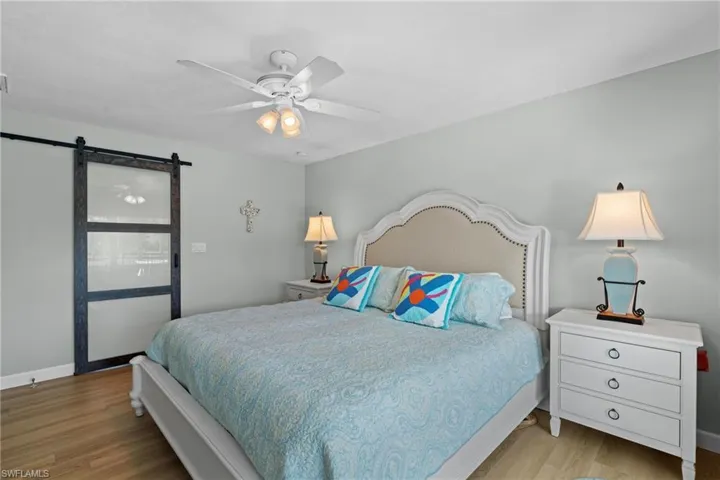 Bedroom featuring a barn door, ceiling fan, and light hardwood / wood-style flooring