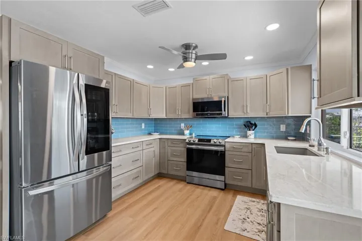 Kitchen featuring sink, light hardwood / wood-style flooring, appliances with stainless steel finishes, tasteful backsplash, and ornamental molding