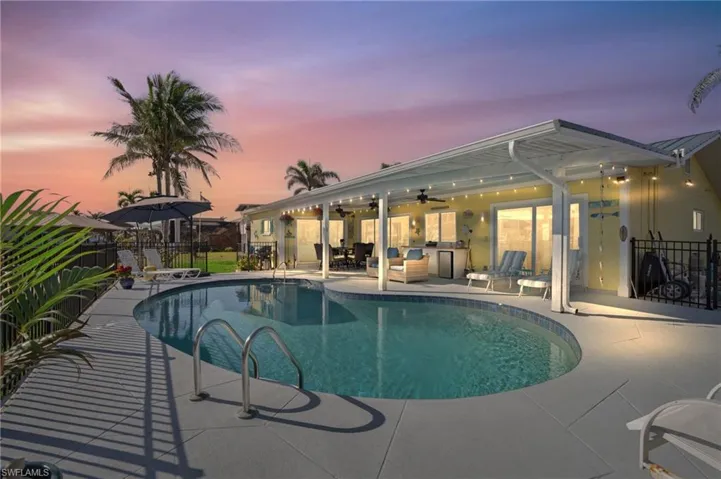 Pool at dusk with a patio area and ceiling fan