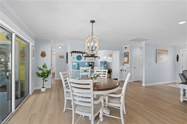 Dining space with ornamental molding, an inviting chandelier, and light hardwood / wood-style floors