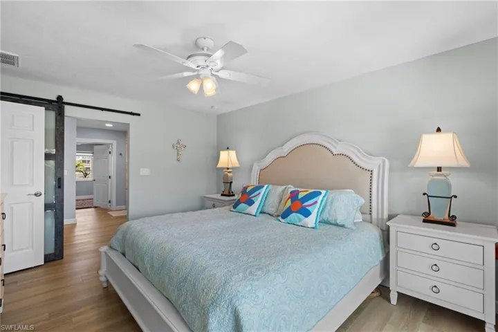 Bedroom featuring light hardwood / wood-style flooring, a barn door, and ceiling fan