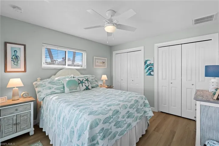 Bedroom with ceiling fan, hardwood / wood-style floors, and two closets
