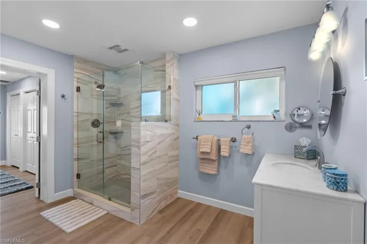 Bathroom featuring vanity, hardwood / wood-style flooring, and a shower with door