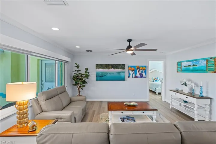 Living room featuring crown molding, ceiling fan, and light wood-type flooring