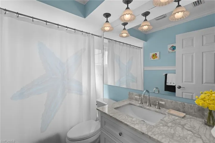 Bathroom with vanity, crown molding, and toilet
