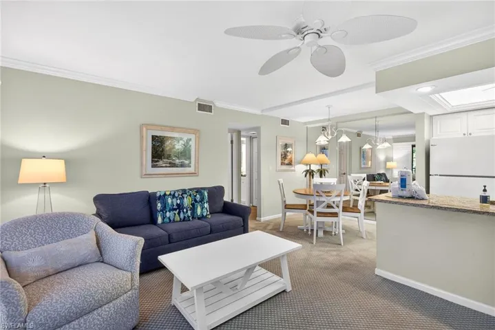 Carpeted living area featuring ornamental molding and a ceiling fan