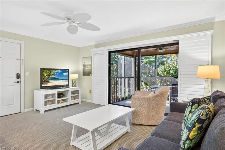 Carpeted living room with crown molding and ceiling fan