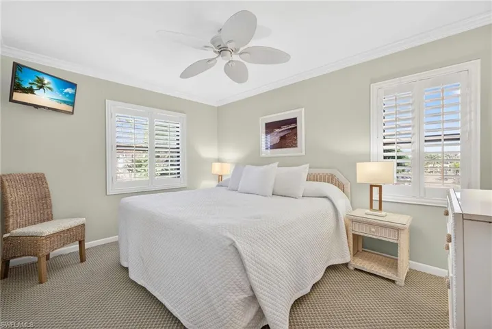Carpeted bedroom with ornamental molding and ceiling fan