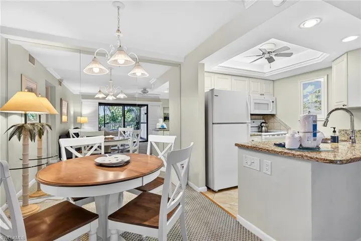 Kitchen with a ceiling fan, white appliances, white cabinetry, light stone counters, and recessed lighting