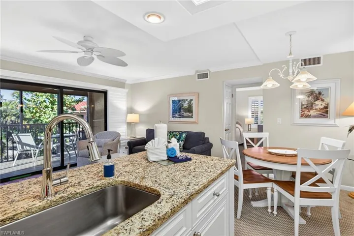 Kitchen featuring white cabinetry, pendant lighting, light stone counters, open floor plan, and plenty of natural light